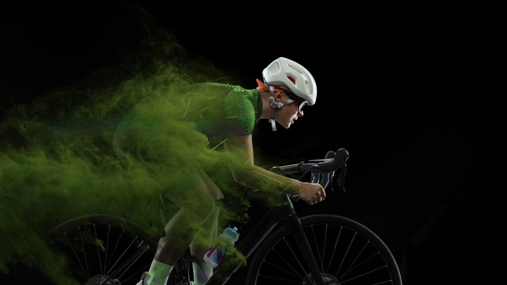 Cyclist racing intensely with green powder trailing behind.