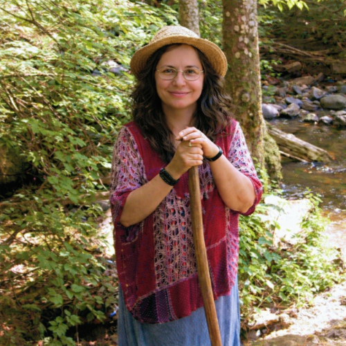 A woman with a dog in a green field under a clear sky.